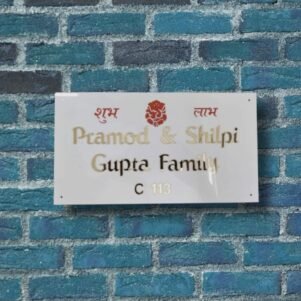 White rectangular name plate with golden letters and red Shubh Labh religious symbols for home entrance