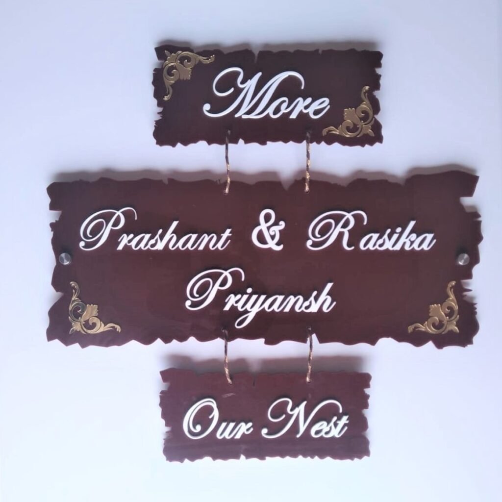 3 piece hanging acrylic name board with dark wood texture and gold corners featuring family names and Our Nest text