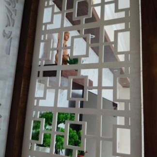 Acrylic jali partition with geometric cut-outs installed beside a pooja room