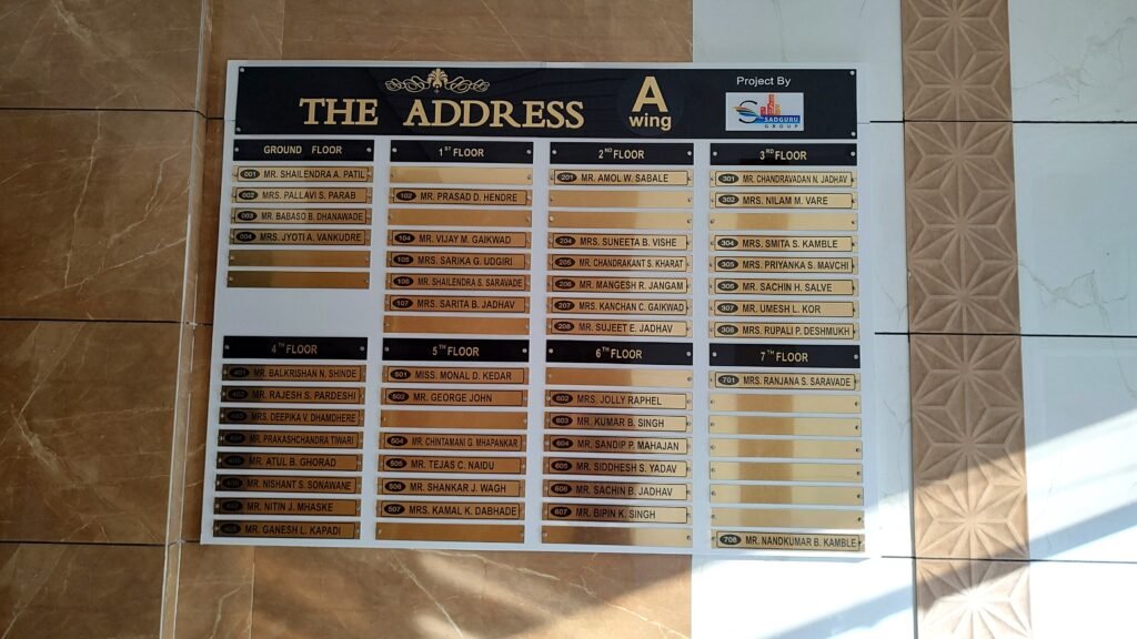 Large black and gold housing society name board for The Address A Wing with floor-wise resident list.