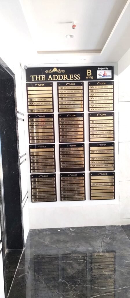 High-rise housing society name board for The Address B Wing listing 12 floors.
