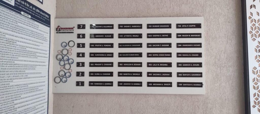 Modern black and white housing society name board for Shashwat Group with geometric circle design.