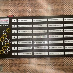 Black housing society name board for Shashwat O-Wing with white name slats and yellow geometric art.